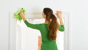 A woman in a green t shirt wiping a door