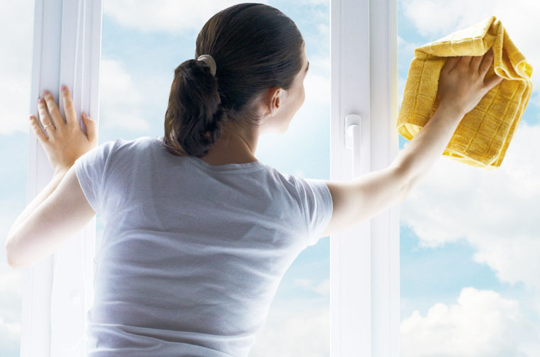 A woman in a white t shirt wiping a window