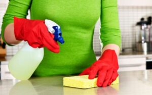 A person in a green shirt holding cleaning spray